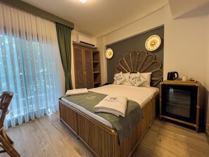 A hotel room with a bed, a wardrobe, a coffee machine, and a view of the outdoors.