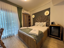 Quarto de hotel com cama, armário, máquina de café e vista para o exterior.