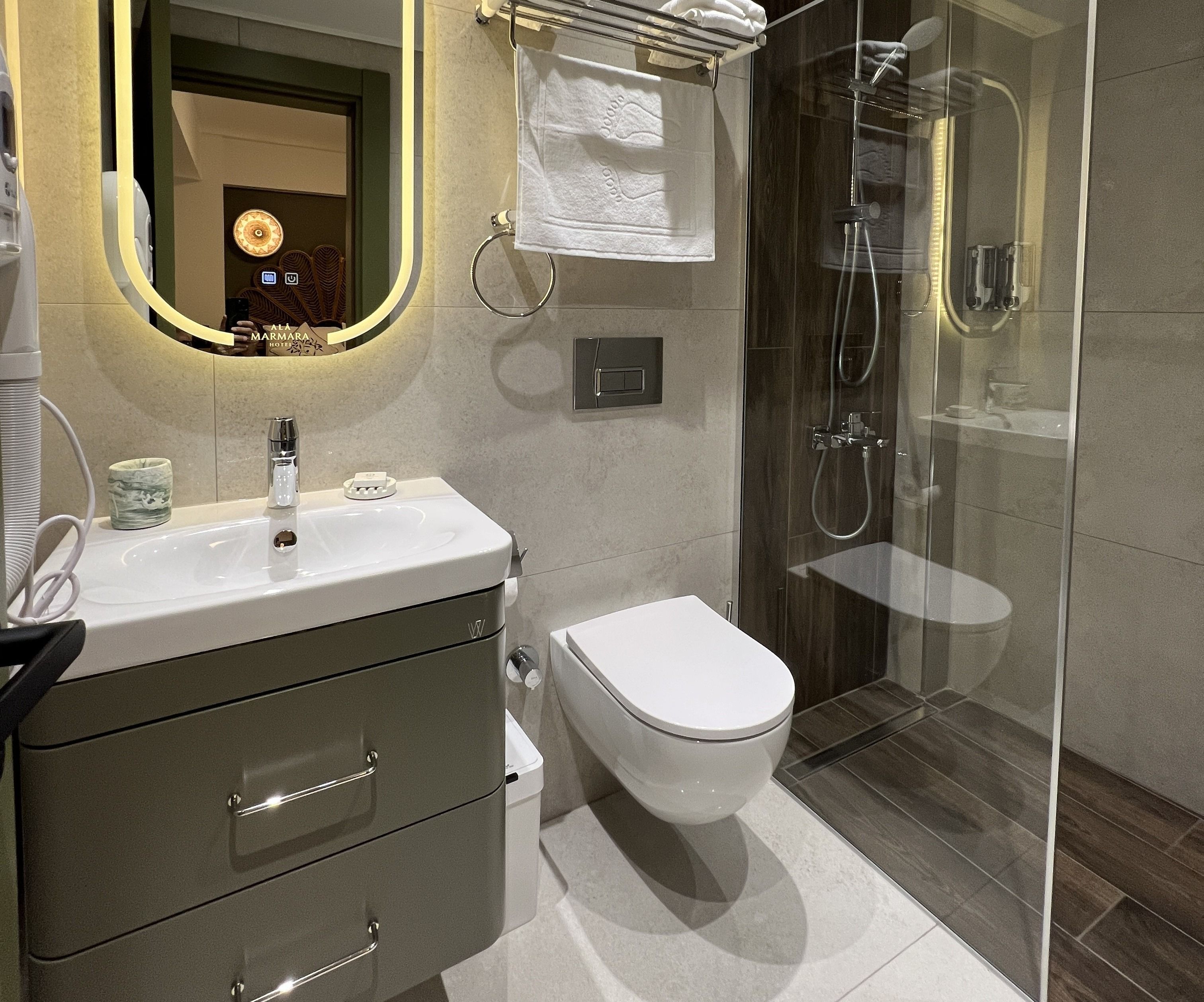 A modern bathroom with a glass-enclosed shower, a white toilet, and a vanity with a mirror.