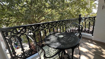 Ein Balkon mit einem Metalltisch und -stühlen, umgeben von einem schmiedeeisernen Geländer.
