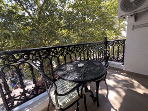 A balcony with a metal table and chair, surrounded by ornate black railings, and a view of trees and a building in the background. - Alâ Marmara Hotel (Marmara)