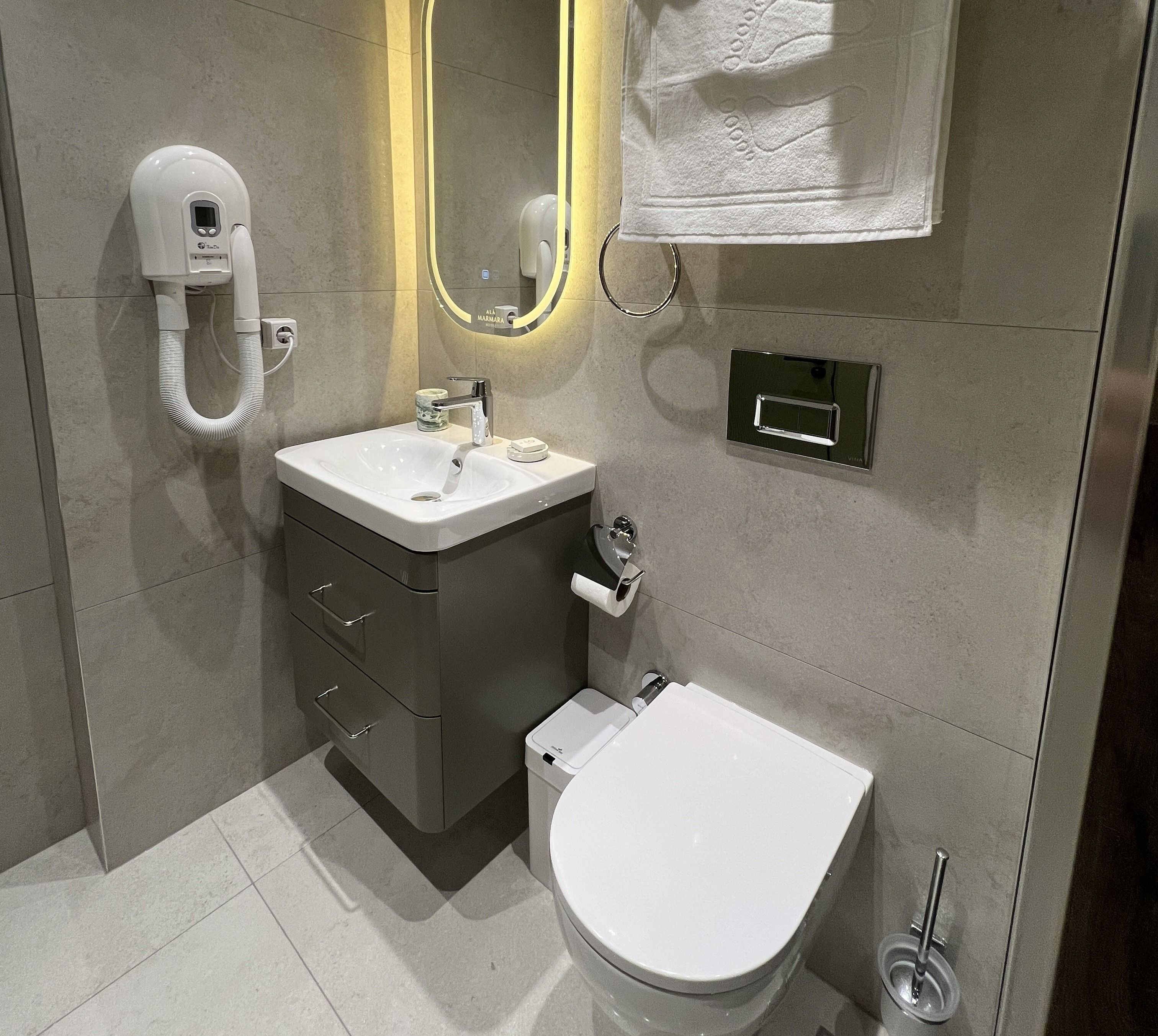 Un baño moderno con inodoro, lavamanos y secamanos.
