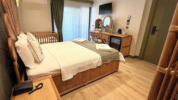 A hotel room with a bed, a desk, a chair, a television, and a wardrobe.