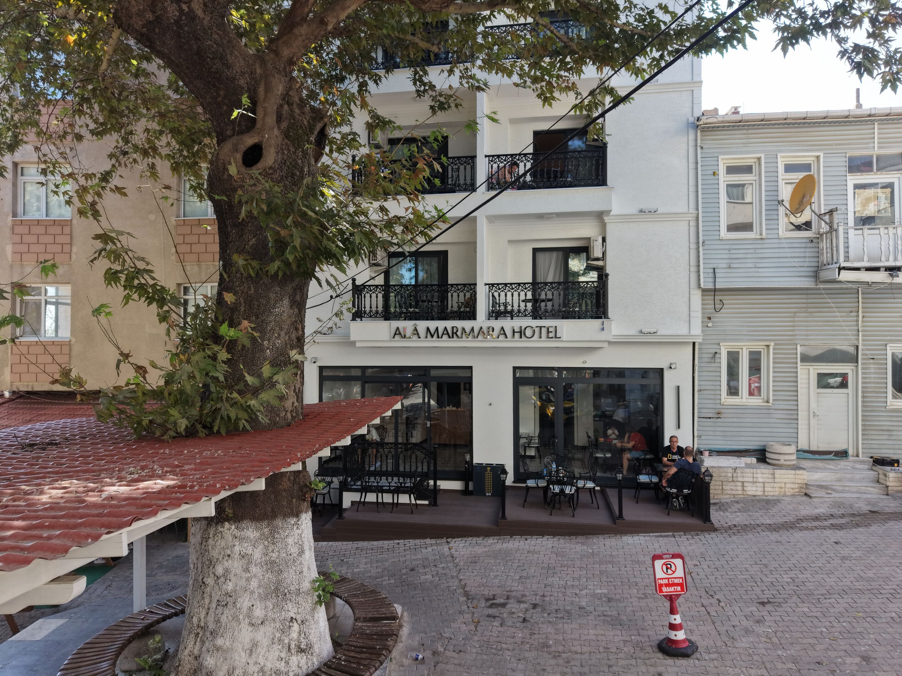 Un hotel con un letrero que dice 'AI AMARAHOTEL' y asientos al aire libre.