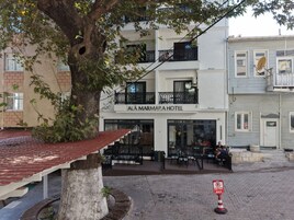 Un hotel con un letrero que dice 'AI AMARAHOTEL' y asientos al aire libre.