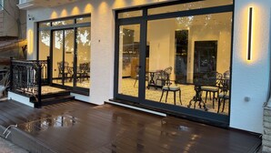 The exterior of Alamarra Hotel with large glass windows, a wooden deck, and a black railing. - Alâ Marmara Hotel (Marmara)
