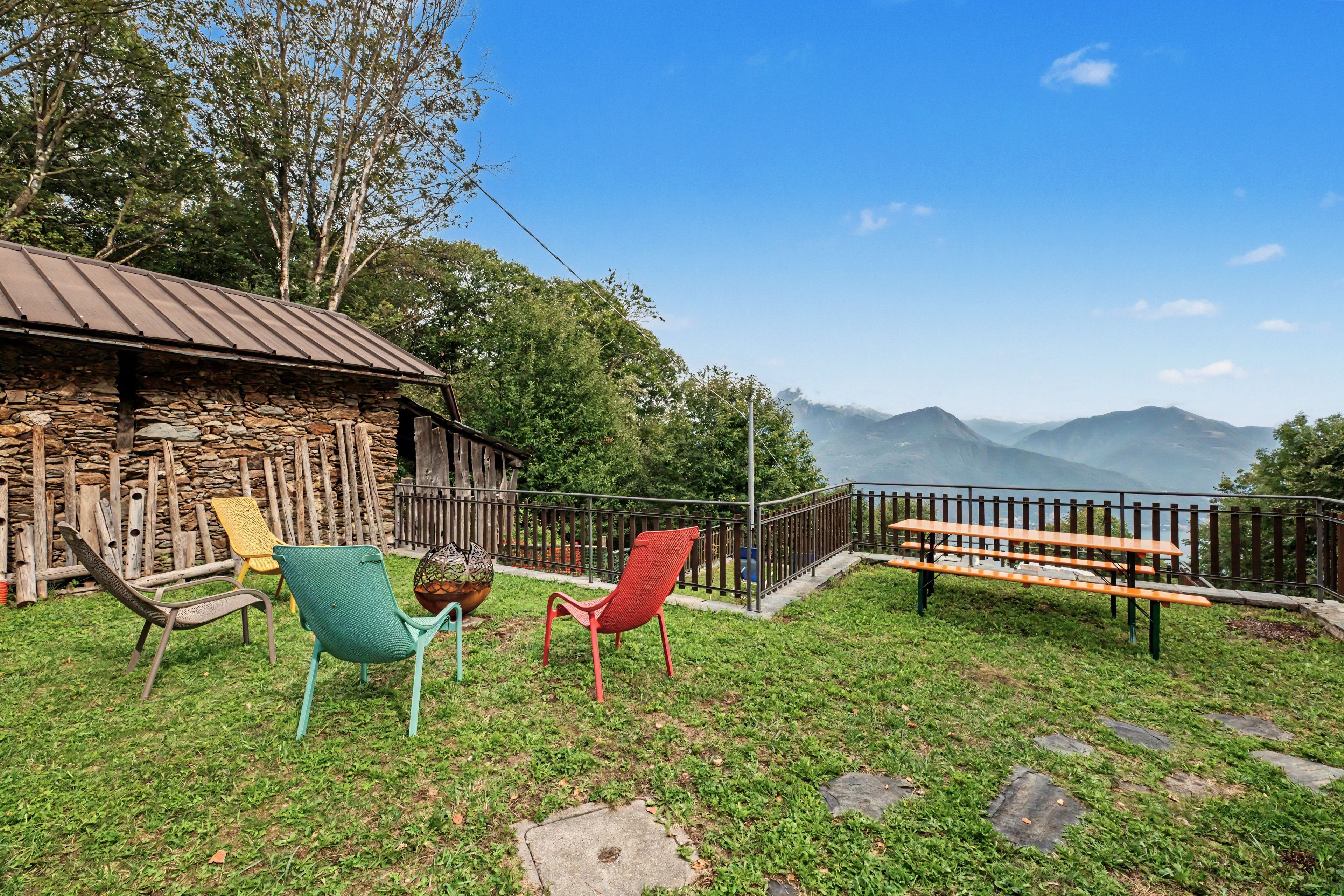 Un espace extérieur aménagé dans un style rustique, avec des murs en pierre, un toit en métal et une vue sur les montagnes.