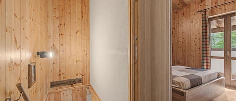 A wooden interior with a bed, a staircase, and a window.