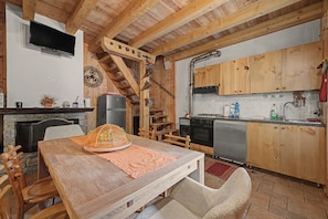 A rustic kitchen with wooden cabinets, a stove, and a dining area with a table and chairs.