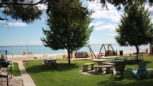 Un'area all'aperto con tavoli da picnic e sedie, altalene e vista sulla spiaggia.