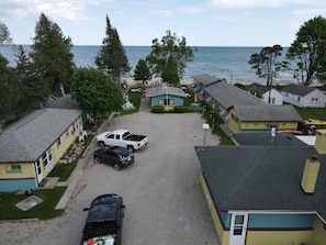 A coastal residential area with houses, a gravel driveway, and a view of the sea. - Family 3-Bedroom Lake Huron Cottage with Beach Access & Scenic Views (Tawas City)