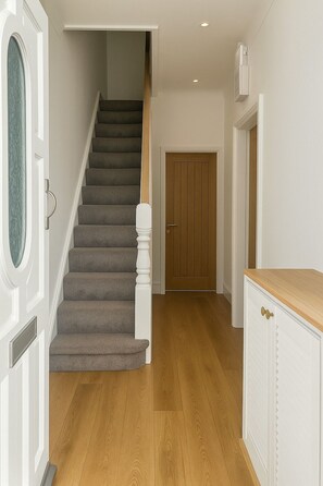 Eine Treppe führt zu einer Holztür, einem weißen Schrank mit einer Holz Arbeitsplatte und einem Lichtschalter an der Wand.