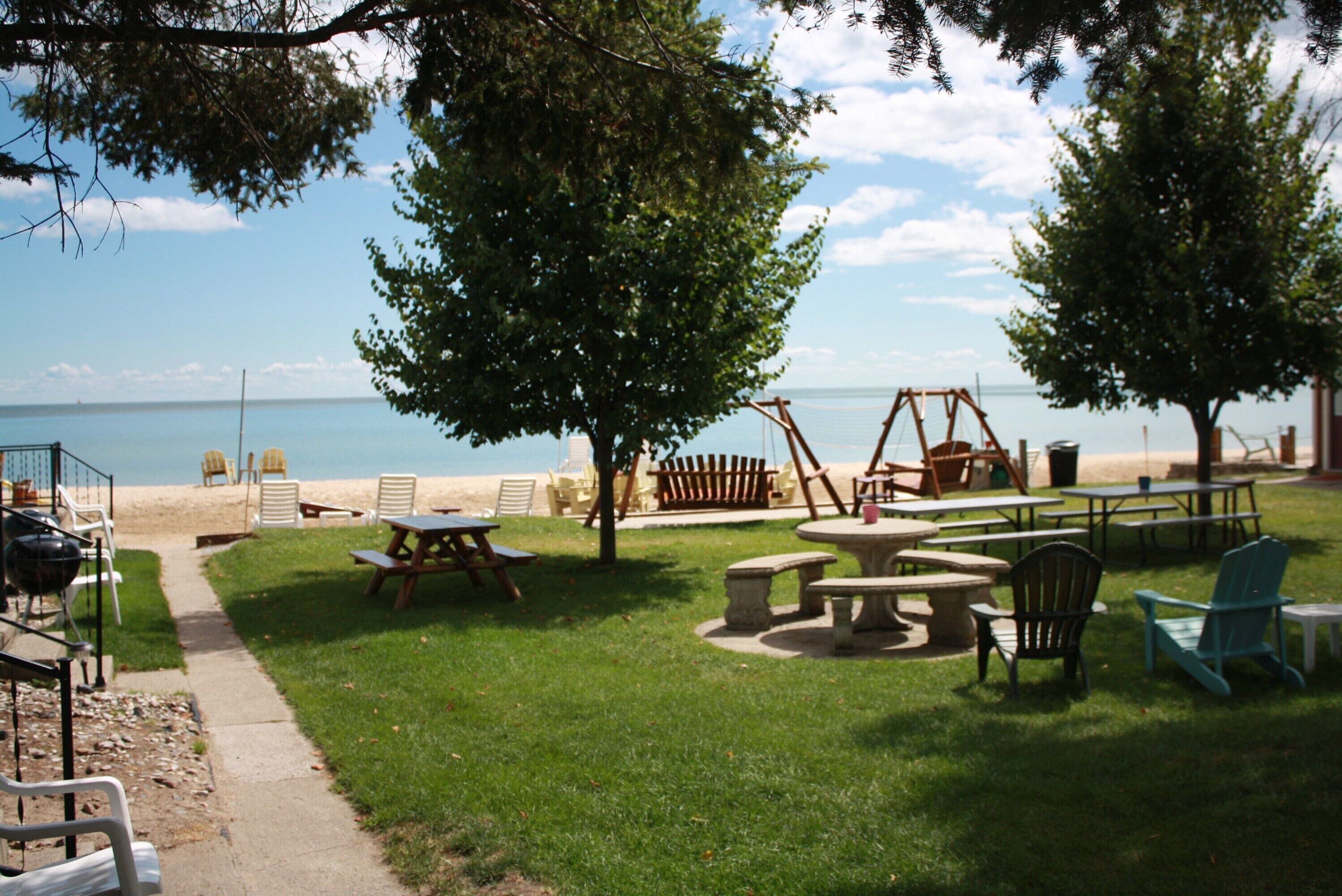 Un espace extérieur aménagé avec des tables et des chaises de pique-nique, une balançoire et une vue sur la plage.