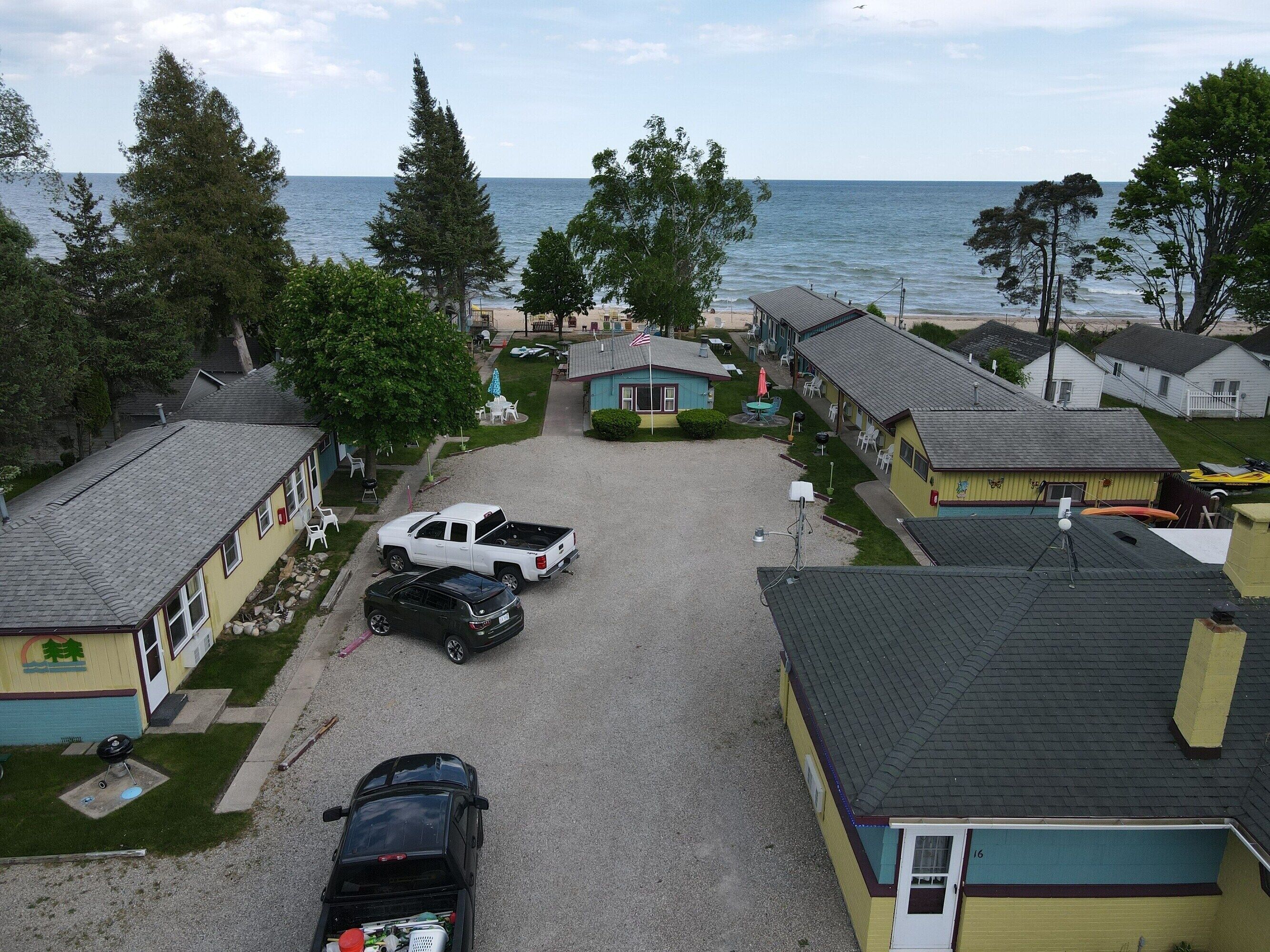 A coastal residential area with houses, a gravel driveway, and a view of the sea.