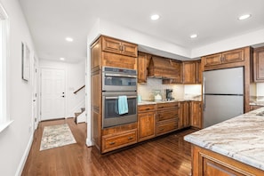 A kitchen with wooden cabinets, stainless steel appliances, and a marble countertop. - Waterfront Retreat Private Pier and Sunset Views (Edgewater)