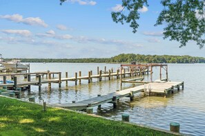 A calm lake with wooden docks extending into the water, surrounded by greenery and a clear sky. - Waterfront Retreat Private Pier and Sunset Views (Edgewater)