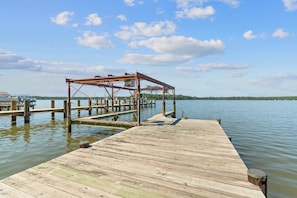 A wooden dock extending into calm water with a metal structure on it. - Waterfront Retreat Private Pier and Sunset Views (Edgewater)