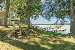 A lakeside property with a covered deck, outdoor seating, and a dock extending into the water. - Waterfront Retreat Private Pier and Sunset Views (Edgewater)