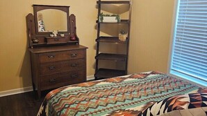 Un dormitorio con cama, cómoda, espejo y ventana con persianas.