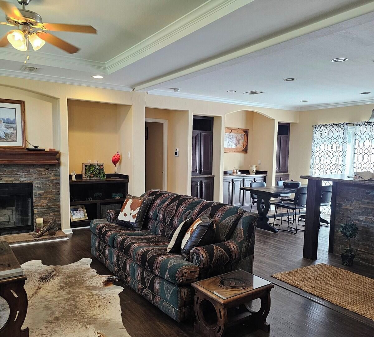 A living room with a patterned sofa, a fireplace, and a dining area with a kitchen in the background.