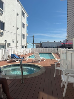 A pool area with two hot tubs, lounge chairs, and a wooden deck. - Ocean Views • 1-BR Ocean City NJ Condo • Beach Block • Boardwalk Ramp • King Bed (Ocean City)