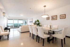 Un comedor moderno con una mesa de vidrio, sillas blancas y una lámpara colgante.