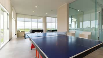 Una habitación amplia con mesa de ping pong, ventanas grandes y vistas al exterior.