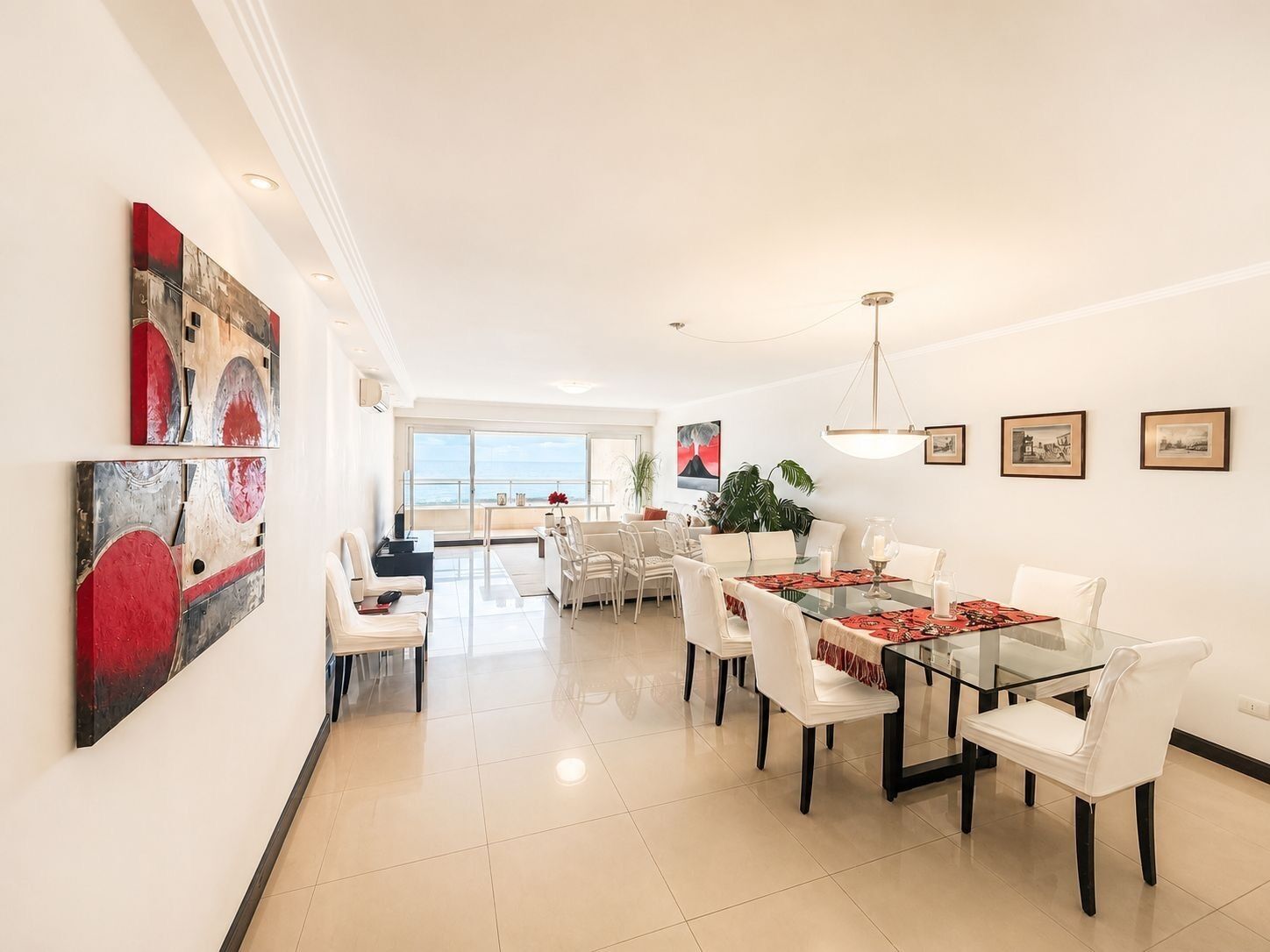 A modern dining area with a glass table, white chairs, and a view to the outside.
