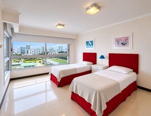 Habitación de hotel con dos camas, un ventanal grande con vistas a la ciudad y una obra de arte en la pared.