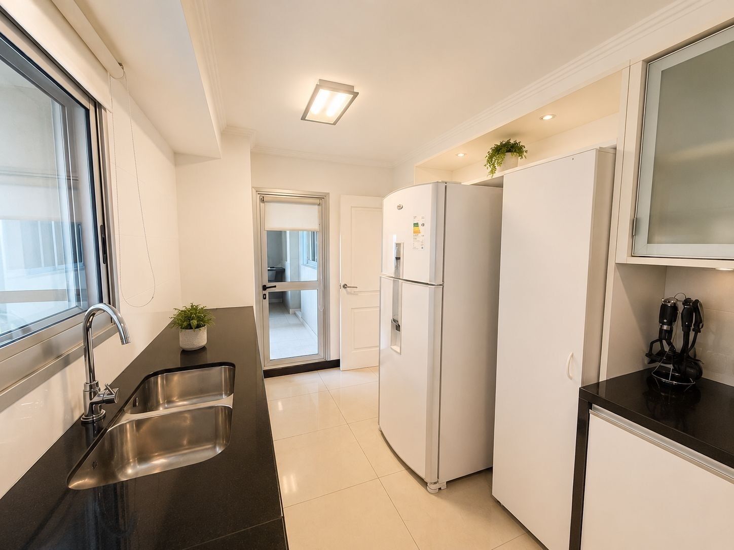 A modern kitchen with a stainless steel sink, a white refrigerator, and a black countertop.