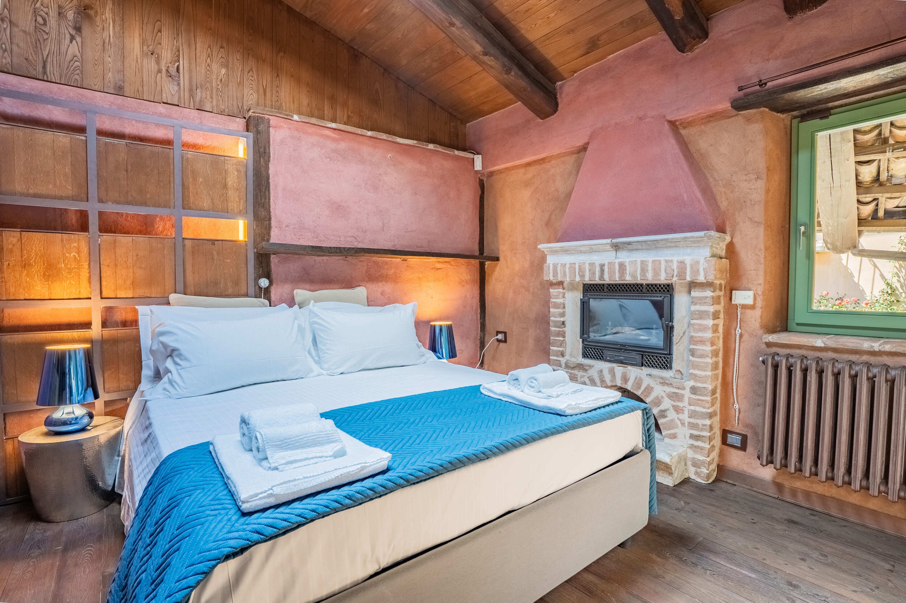 Une chambre à coucher avec un grand lit, une cheminée et des murs en bois.