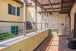 Ein überdachter Außenbereich mit Steinwand, Metallgeländer und Fliesenboden.