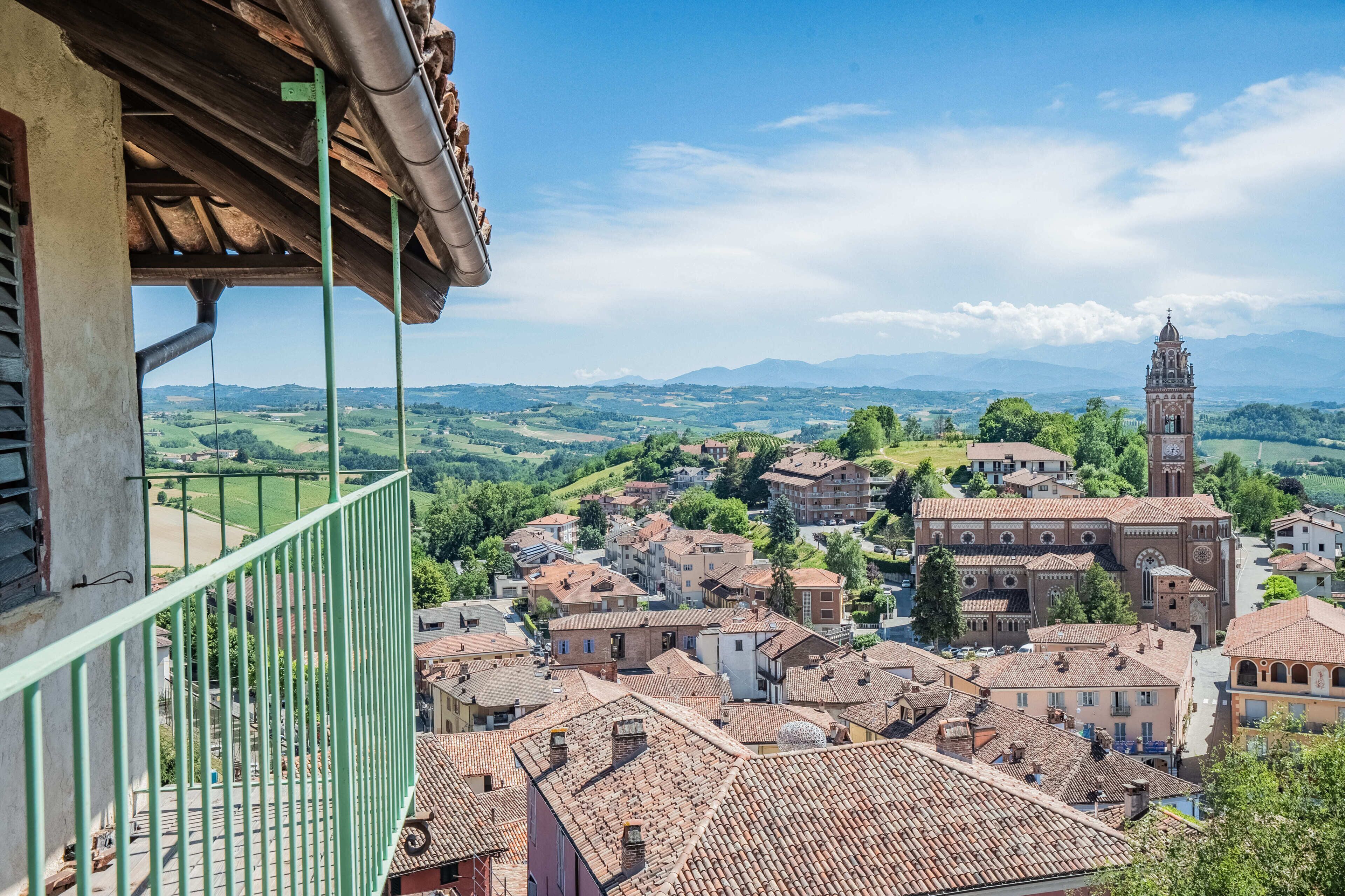 Un balcon offrant une vue sur une ville avec des bâtiments historiques et un clocher d’église imposant.