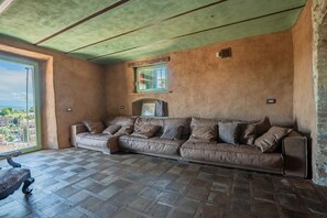 Ein Zimmer mit einem braunen Ledersofa, einem Fenster mit Blick und einem gemusterten Boden.