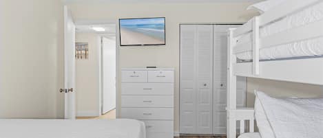 Ein Schlafzimmer mit Etagenbetten, einem Schminktisch, einem Fernseher und einem Kleiderschrank.