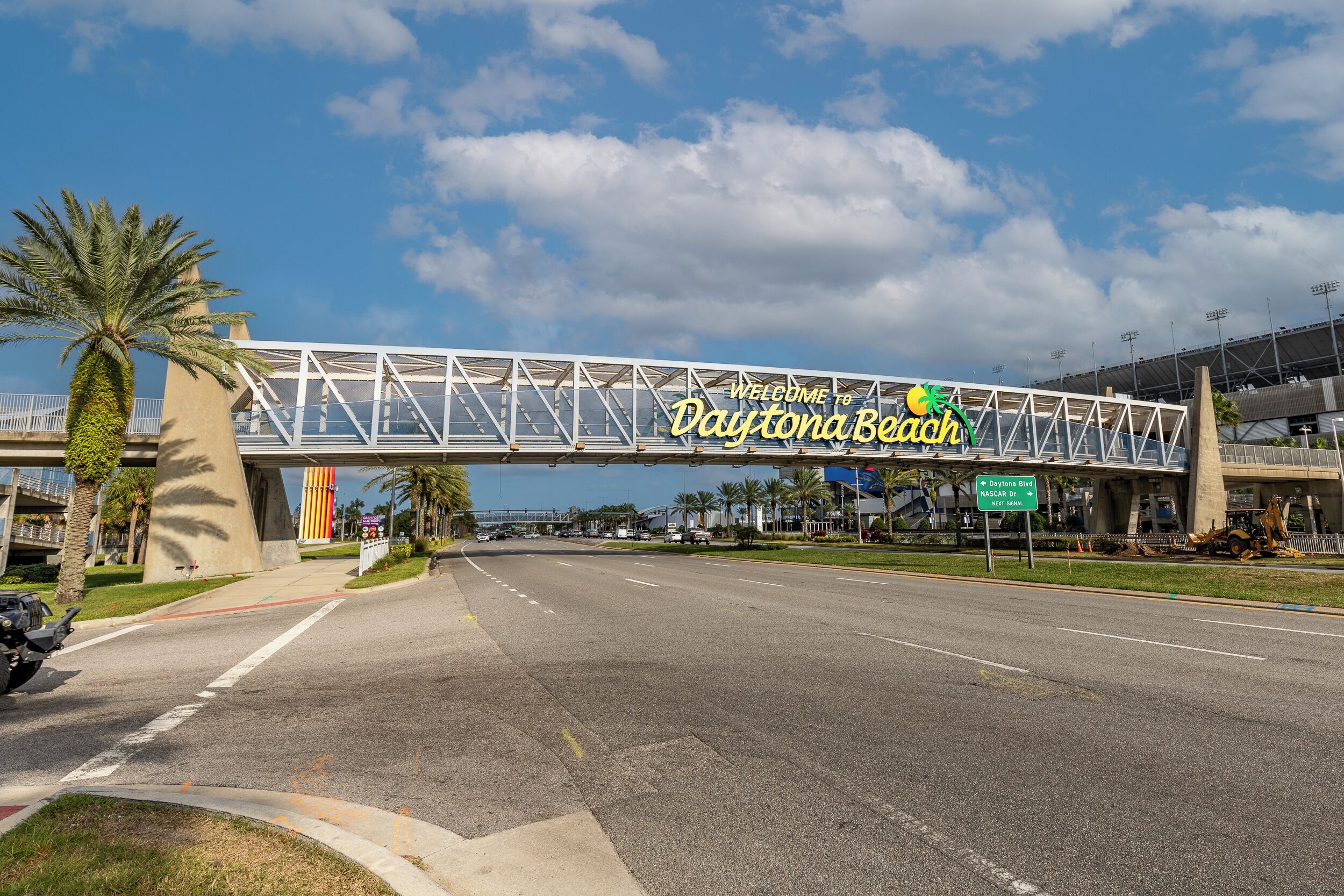 A road leading to a stadium with a sign reading "Welcome to Daytona Beach."