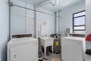 A compact laundry room with two washing machines, a sink, and a window. - 🏁 Ocean Terrace Club 107 | Ground Floor | Steps to Daytona Beach (Daytona Beach Shores)