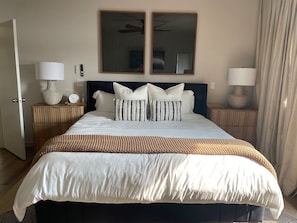 Een hotelkamer met een bed, nachtkastjes, lampen, een klok en een spiegel.