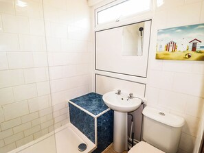 A bathroom with white tiled walls, a blue marble sink, a toilet, and a shower. - Chalet 242 Carmarthen Bay (Kidwelly)