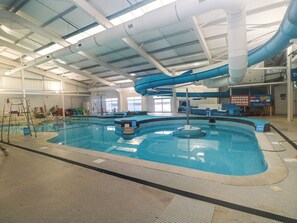 An indoor swimming pool with a slide, depth markers, and a lifeguard stand. - Chalet 242 Carmarthen Bay (Kidwelly)