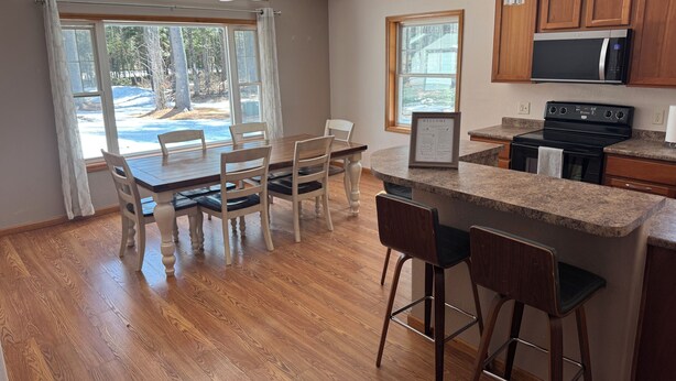 A modern kitchen with wooden cabinets, a black microwave, and a stainless steel stove. - Timberville - Hank (Gwinn)