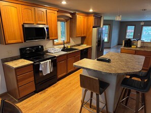 Una cocina moderna con armarios de madera, un refrigerador de acero inoxidable, un microondas y una encimera de granito.