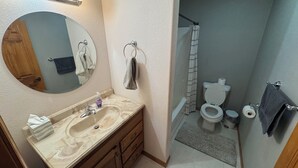 A bathroom with a sink, mirror, towel rack, toilet, and shower curtain. - Timberville - Hank (Gwinn)
