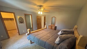 A bedroom with a bed, a ceiling fan, a dresser, and a mirror. - Timberville - Hank (Gwinn)