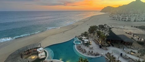 A resort with a pool, lounge areas, and a beach view.