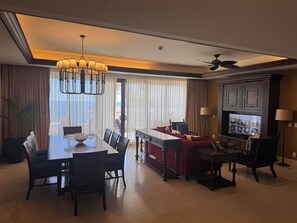 Quarto de hotel com área de jantar, sofá, televisão e ventoinha no teto.