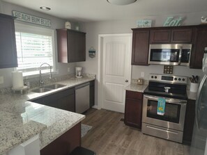 A kitchen with a granite countertop, stainless steel appliances, and wooden cabinets.
