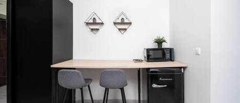 A compact kitchenette with a microwave, a small refrigerator, and two chairs.