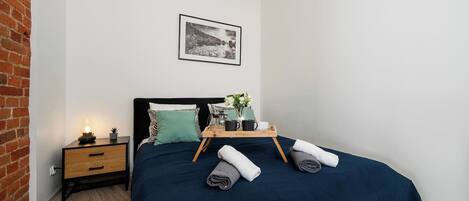 Un dormitorio con una cama, una mesita de noche, un cuadro enmarcado en la pared y una pared de ladrillo.