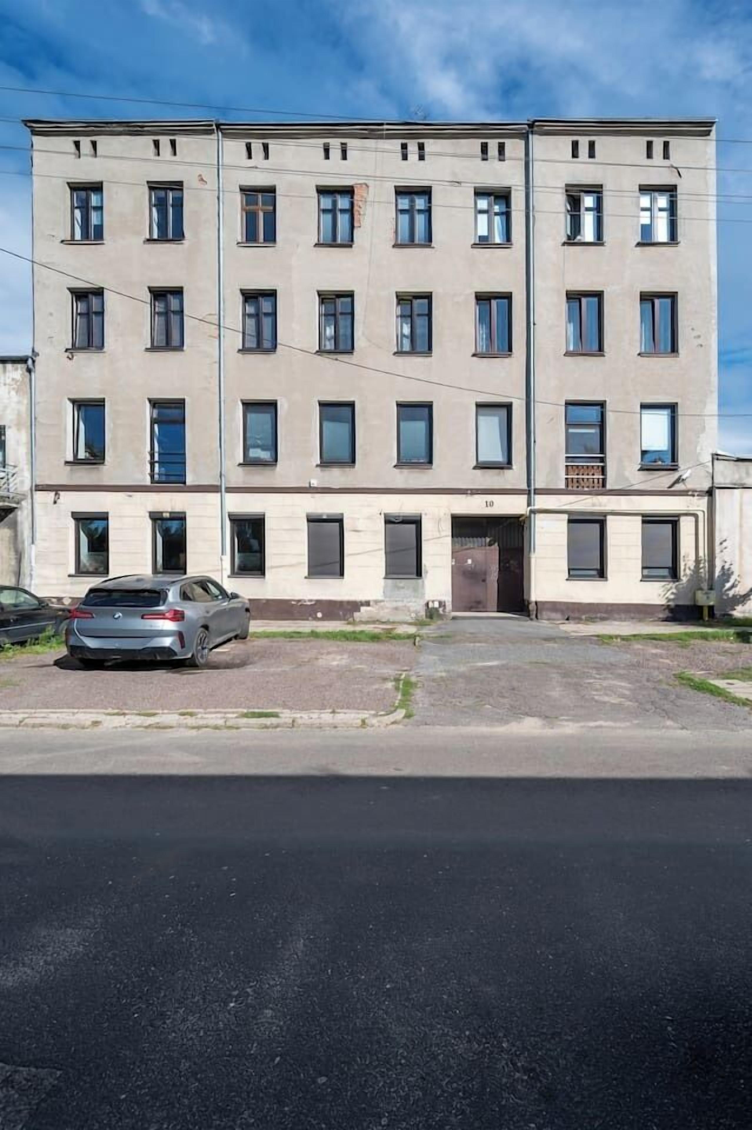 En byggnad med flera våningar och en slät fasad, med flera fönster och en bil parkerad framför.